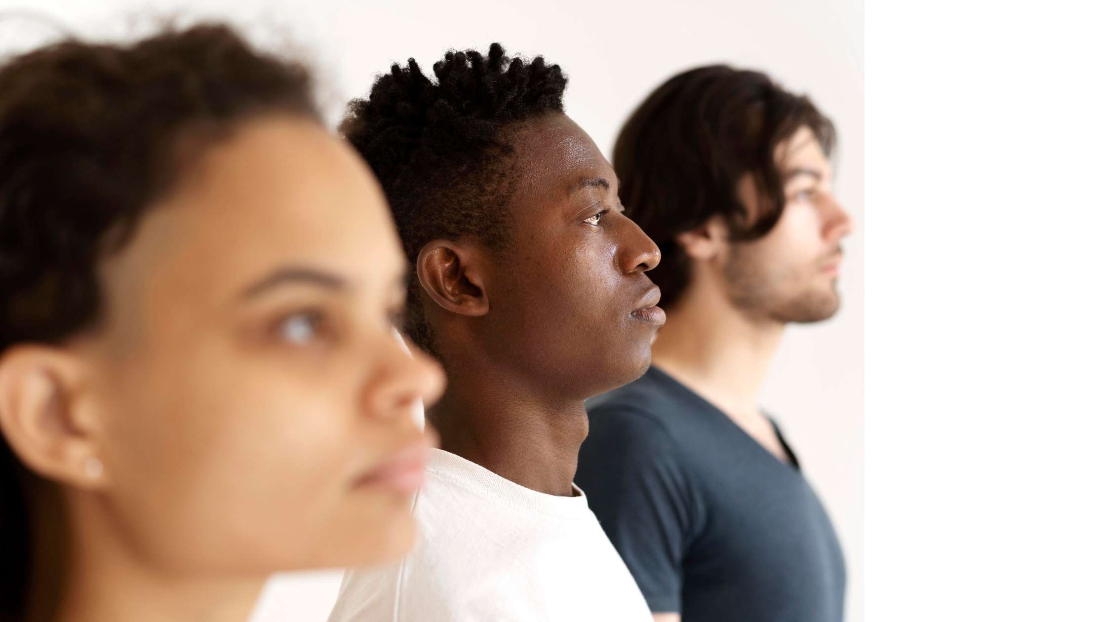 Três pessoas uma ao lado da outra, olhando para a mesma direção.