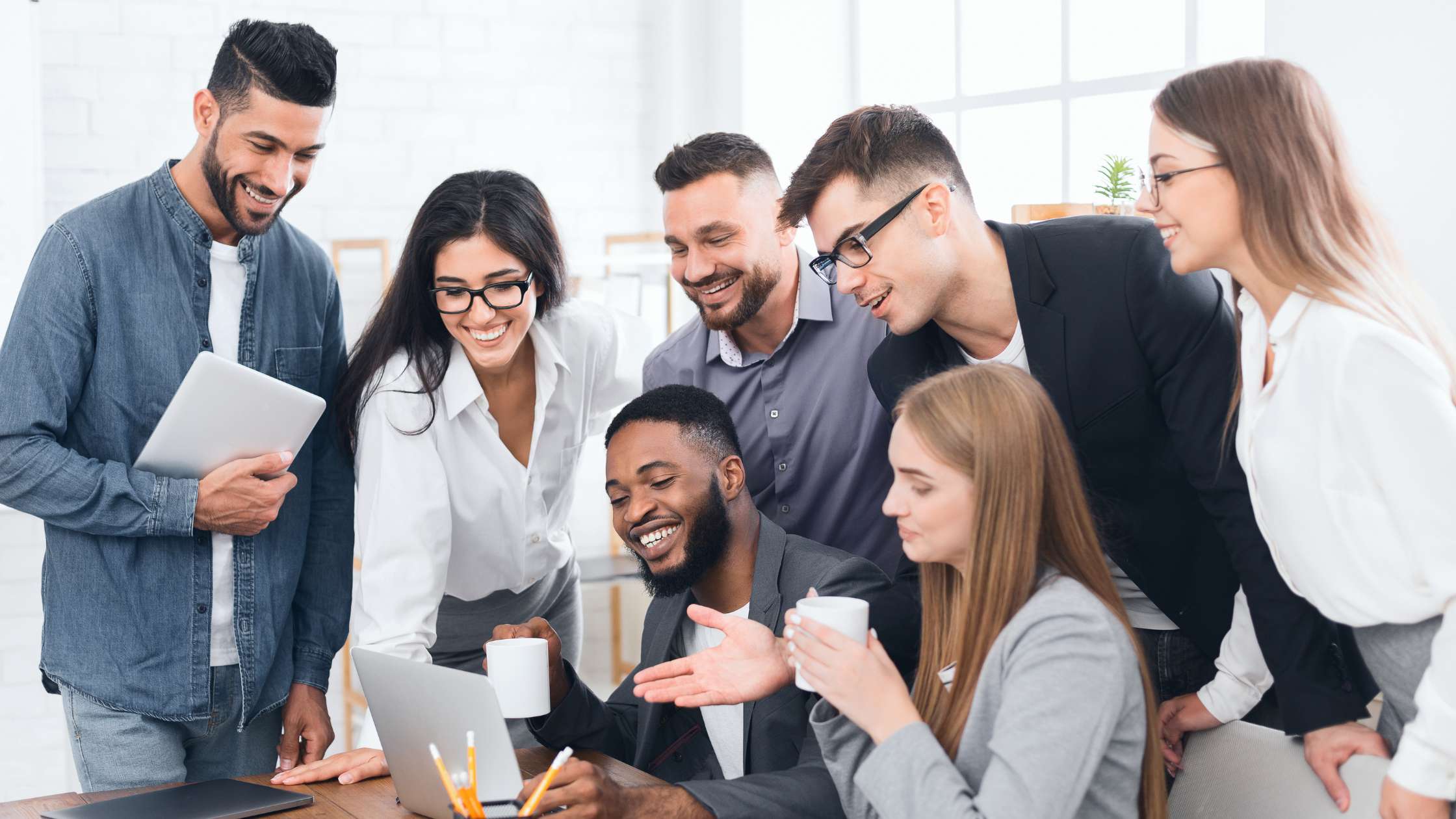 7 pessoas juntas em um ambiente de trabalho. Em frente ao computador fazendo um planejamento estratégico.